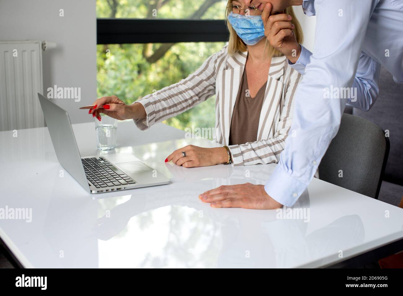 Uomini d'affari, donne e uomini con maschera aganista covid che parla di fronte al computer portatile in sala di lavoro. Coronavirus nel lavoro. Covid-19 in ufficio. Buissnes Foto Stock