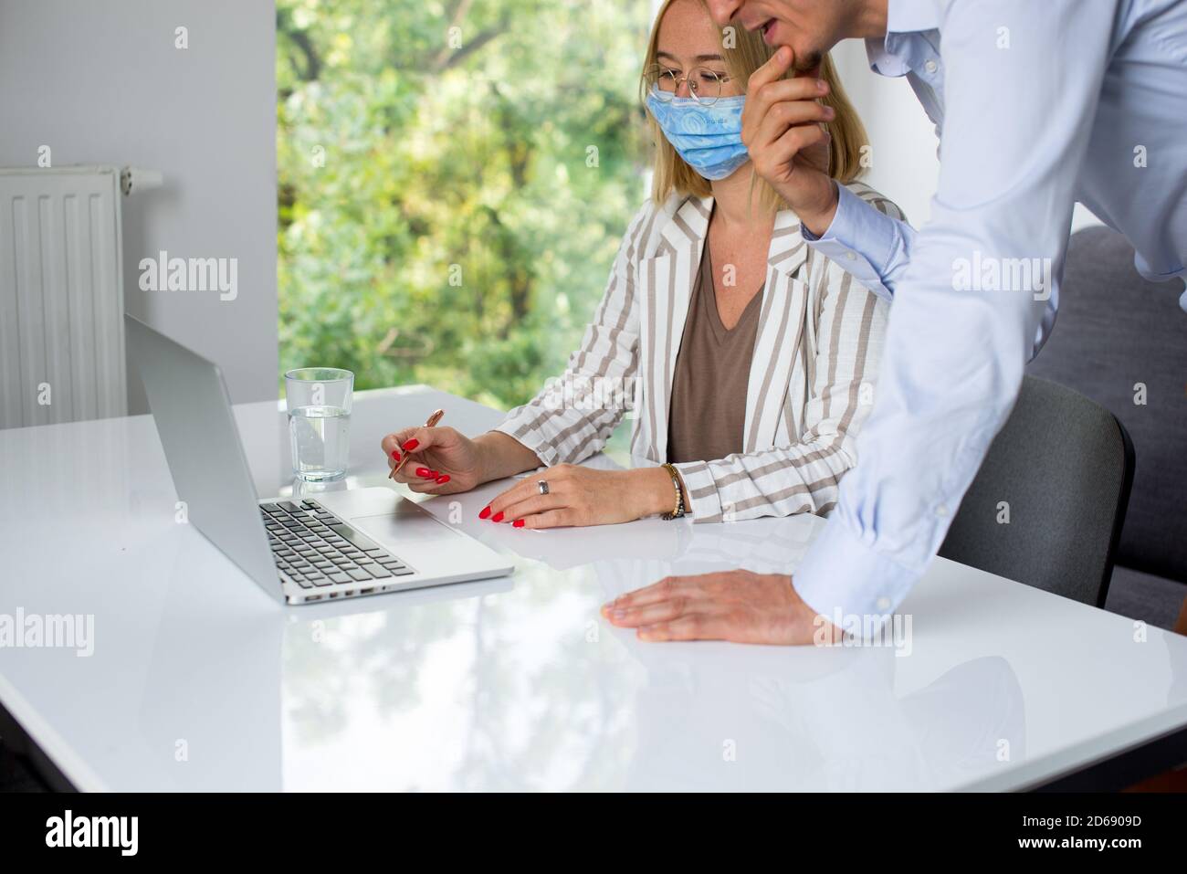 Uomini d'affari, donne e uomini con maschera aganista covid che parla di fronte al computer portatile in sala di lavoro. Coronavirus nel lavoro. Covid-19 in ufficio. Buissnes Foto Stock