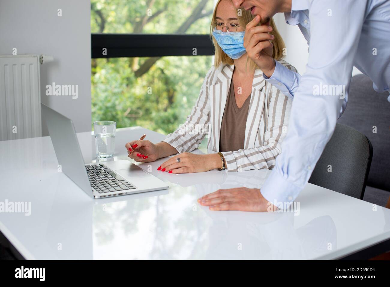 Uomini d'affari, donne e uomini con maschera aganista covid che parla di fronte al computer portatile in sala di lavoro. Coronavirus nel lavoro. Covid-19 in ufficio. Buissnes Foto Stock