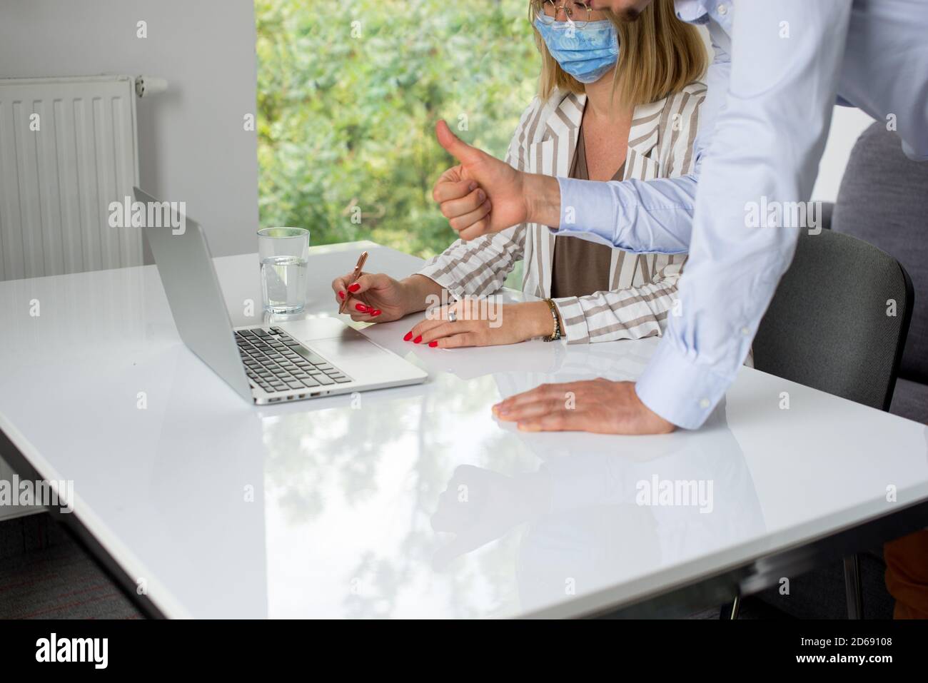 Uomini d'affari, donne e uomini con maschera aganista covid che parla di fronte al computer portatile in sala di lavoro. Coronavirus nel lavoro. Covid-19 in ufficio. Buissnes Foto Stock