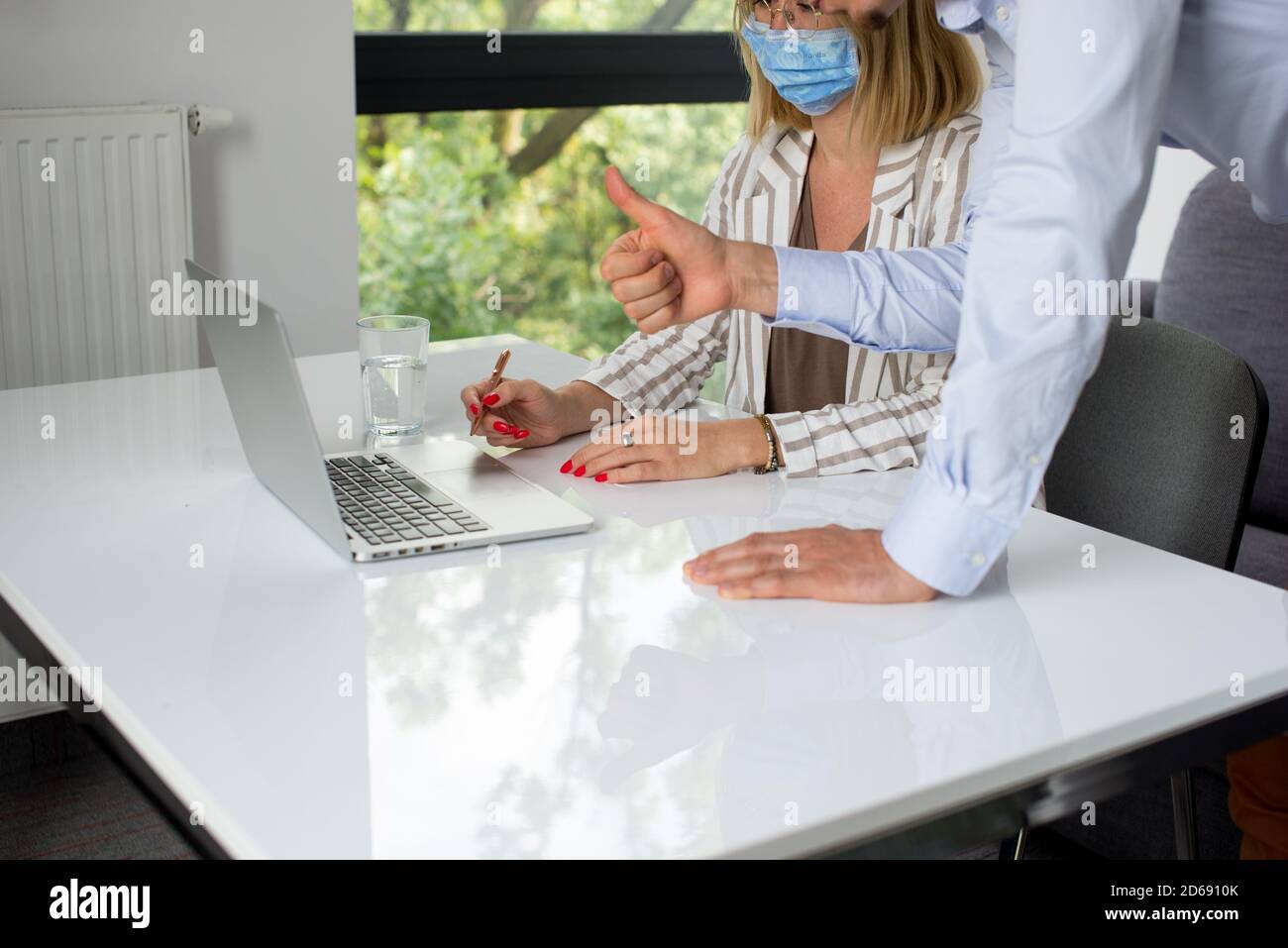 Uomini d'affari, donne e uomini con maschera aganista covid che parla di fronte al computer portatile in sala di lavoro. Coronavirus nel lavoro. Covid-19 in ufficio. Buissnes Foto Stock