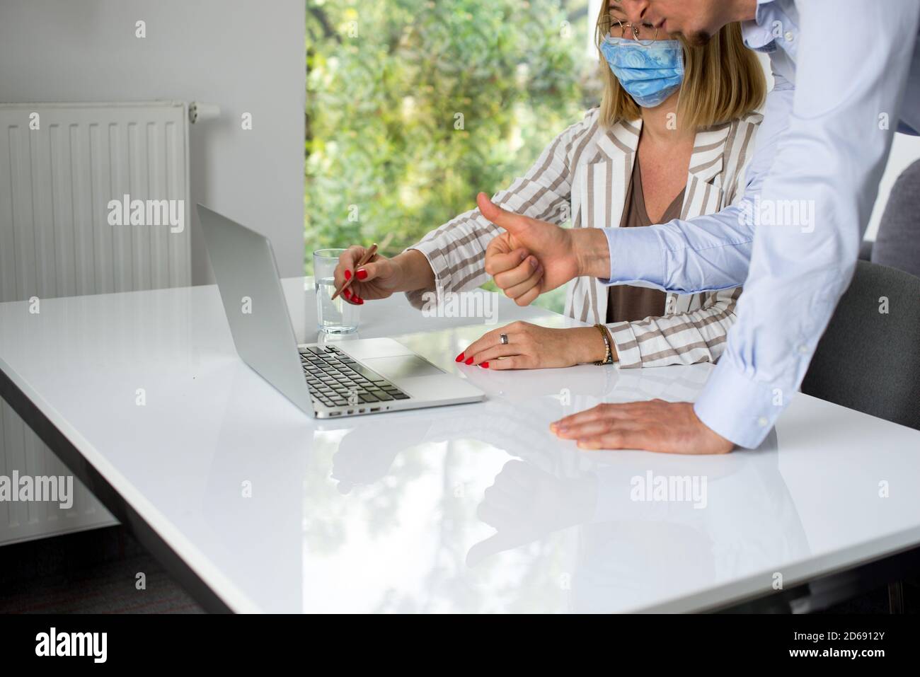 Uomini d'affari, donne e uomini con maschera aganista covid che parla di fronte al computer portatile in sala di lavoro. Coronavirus nel lavoro. Covid-19 in ufficio. Buissnes Foto Stock