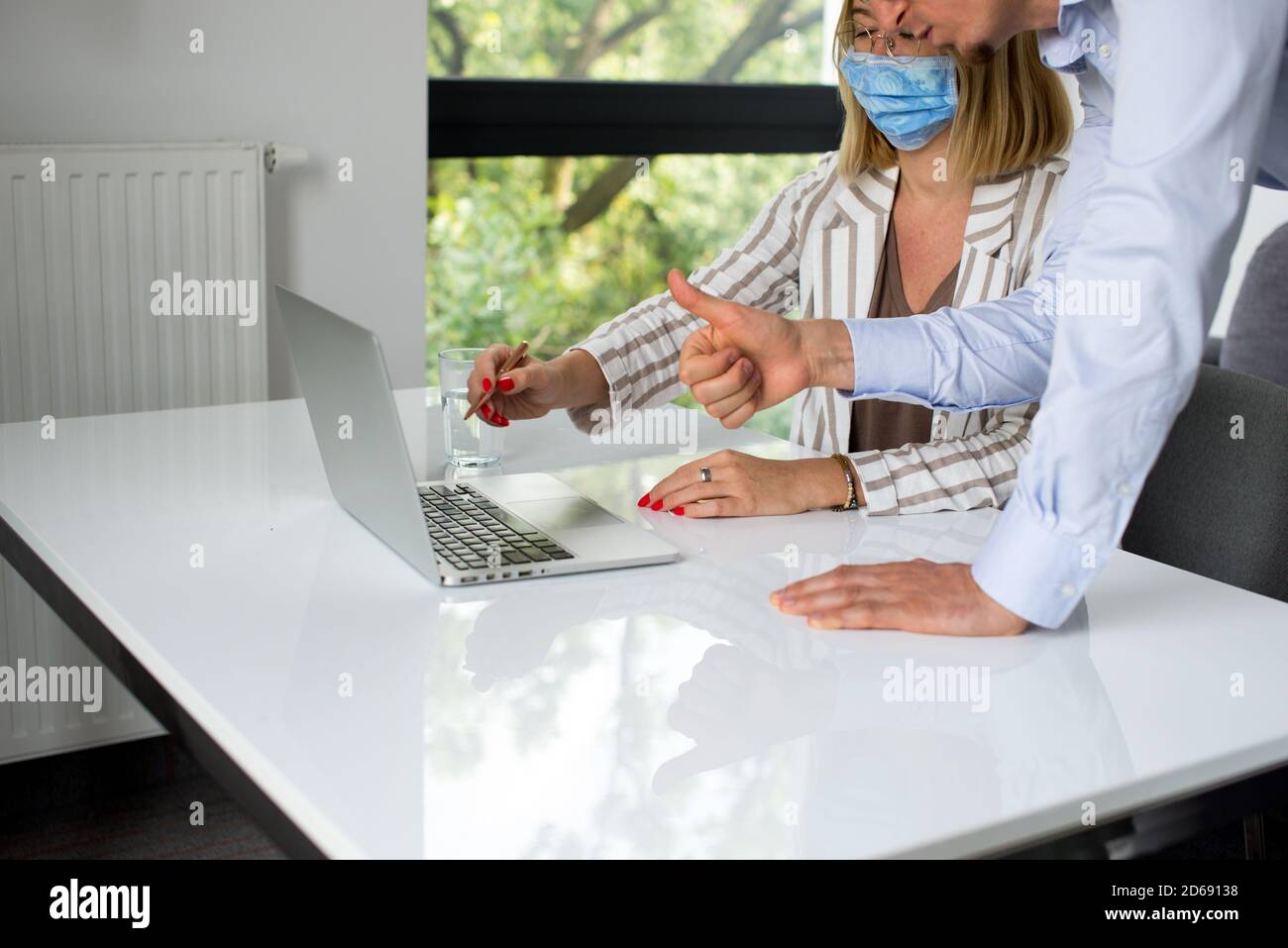 Uomini d'affari, donne e uomini con maschera aganista covid che parla di fronte al computer portatile in sala di lavoro. Coronavirus nel lavoro. Covid-19 in ufficio. Buissnes Foto Stock
