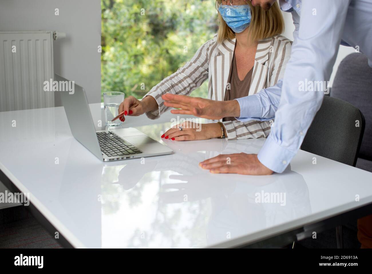Uomini d'affari, donne e uomini con maschera aganista covid che parla di fronte al computer portatile in sala di lavoro. Coronavirus nel lavoro. Covid-19 in ufficio. Buissnes Foto Stock