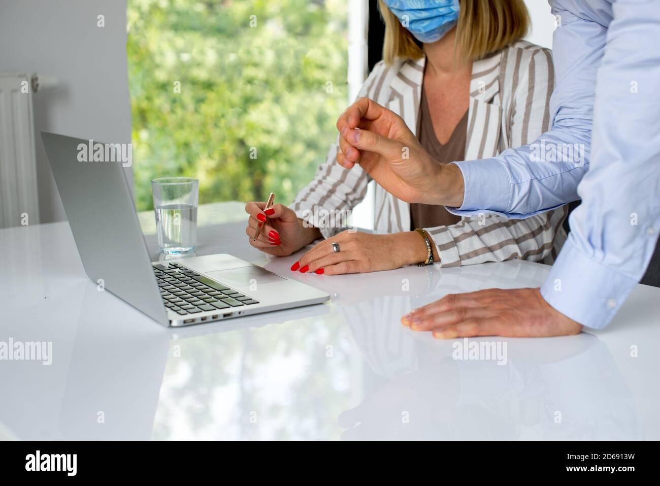 Uomini d'affari, donne e uomini con maschera aganista covid che parla di fronte al computer portatile in sala di lavoro. Coronavirus nel lavoro. Covid-19 in ufficio. Buissnes Foto Stock