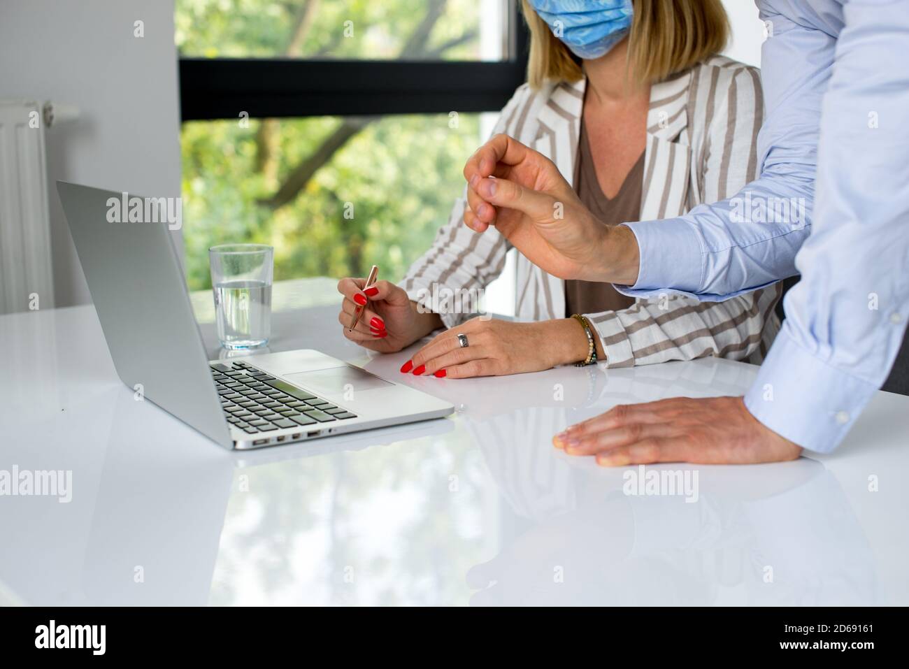 Uomini d'affari, donne e uomini con maschera aganista covid che parla di fronte al computer portatile in sala di lavoro. Coronavirus nel lavoro. Covid-19 in ufficio. Buissnes Foto Stock