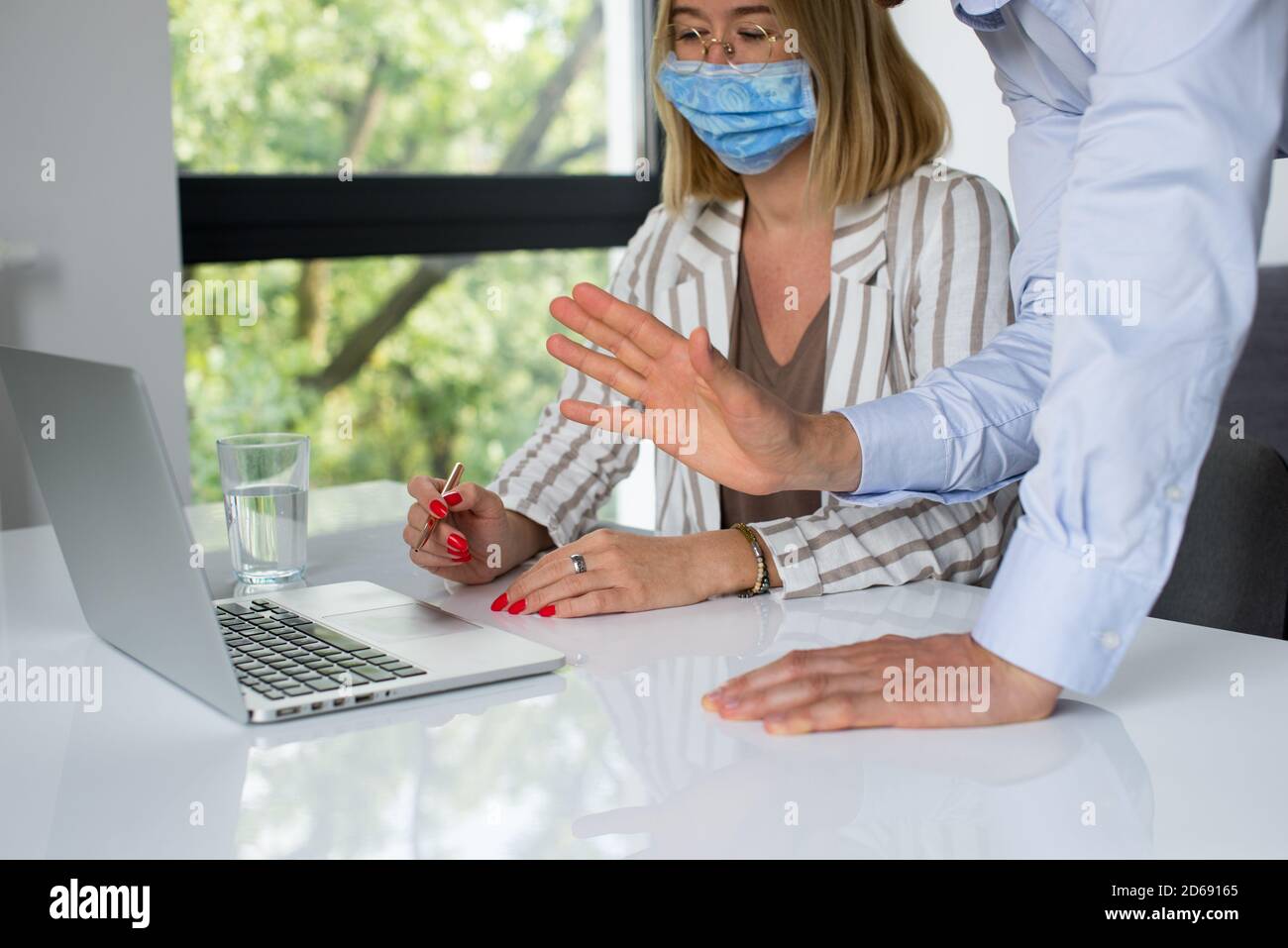 Uomini d'affari, donne e uomini con maschera aganista covid che parla di fronte al computer portatile in sala di lavoro. Coronavirus nel lavoro. Covid-19 in ufficio. Buissnes Foto Stock