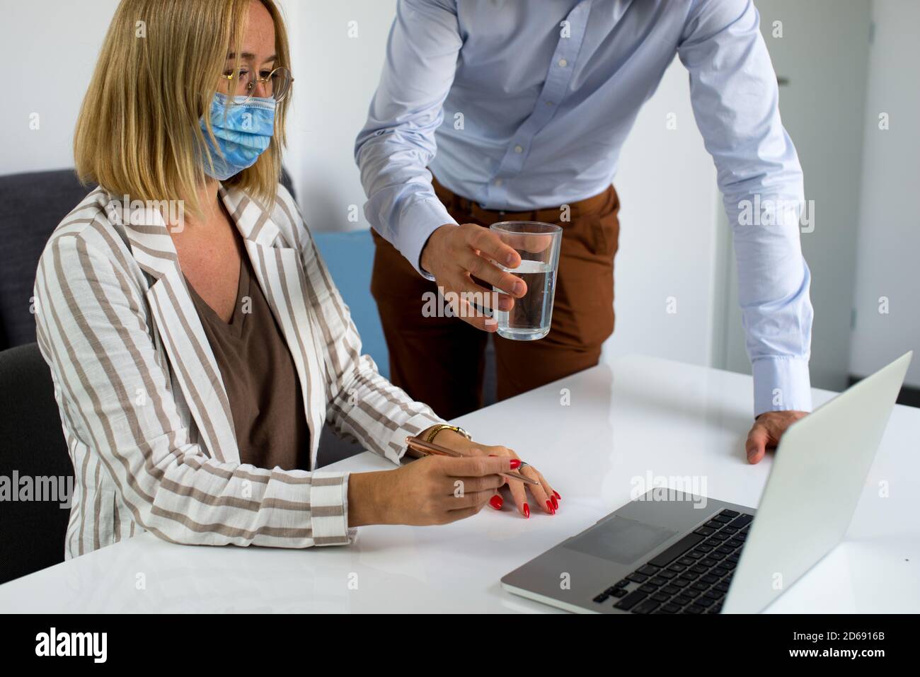 Uomini d'affari, donne e uomini con maschera aganista covid che parla di fronte al computer portatile in sala di lavoro. Coronavirus nel lavoro. Covid-19 in ufficio. Buissnes Foto Stock