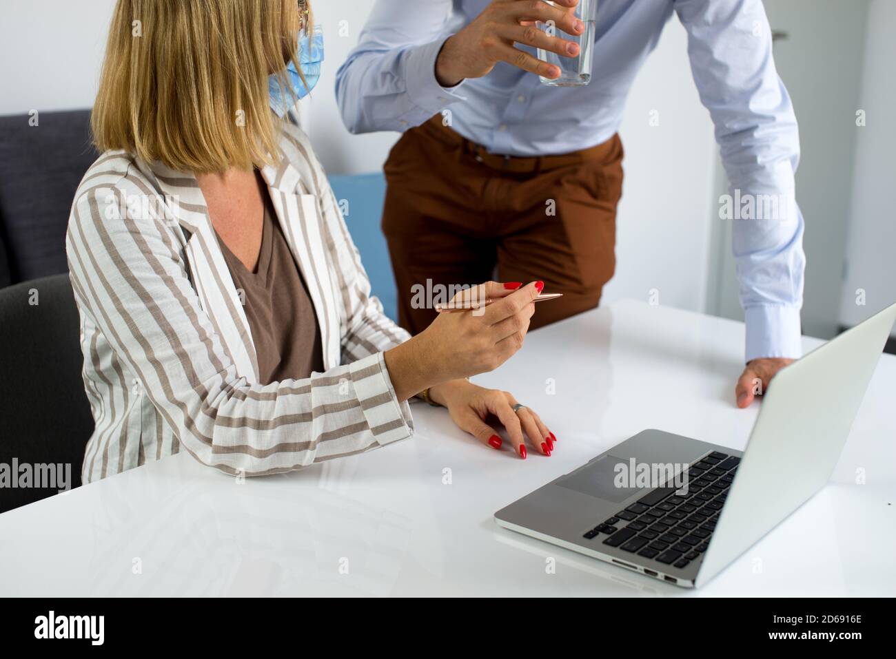 Uomini d'affari, donne e uomini con maschera aganista covid che parla di fronte al computer portatile in sala di lavoro. Coronavirus nel lavoro. Covid-19 in ufficio. Buissnes Foto Stock