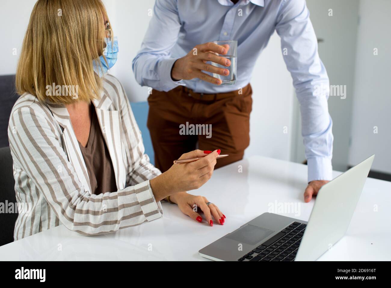Uomini d'affari, donne e uomini con maschera aganista covid che parla di fronte al computer portatile in sala di lavoro. Coronavirus nel lavoro. Covid-19 in ufficio. Buissnes Foto Stock