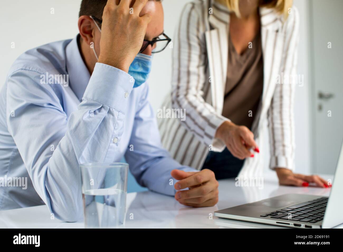 Uomini d'affari, donne e uomini con maschera aganista covid che parla di fronte al computer portatile in sala di lavoro. Coronavirus nel lavoro. Covid-19 in ufficio. Buissnes Foto Stock