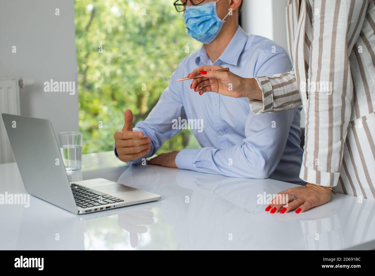 Uomini d'affari, donne e uomini con maschera aganista covid che parla di fronte al computer portatile in sala di lavoro. Coronavirus nel lavoro. Covid-19 in ufficio. Buissnes Foto Stock