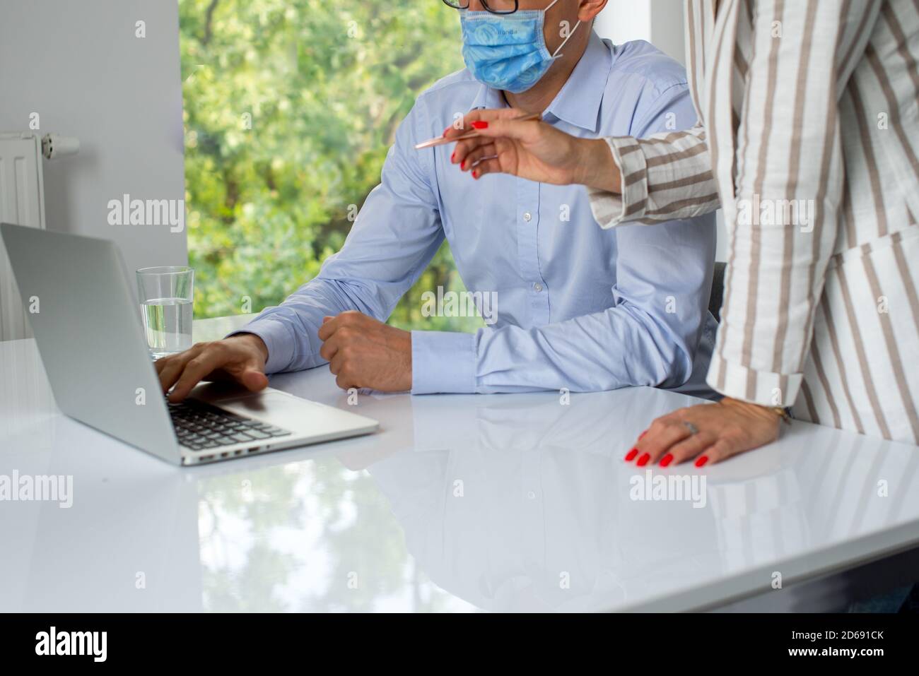 Uomini d'affari, donne e uomini con maschera aganista covid che parla di fronte al computer portatile in sala di lavoro. Coronavirus nel lavoro. Covid-19 in ufficio. Buissnes Foto Stock