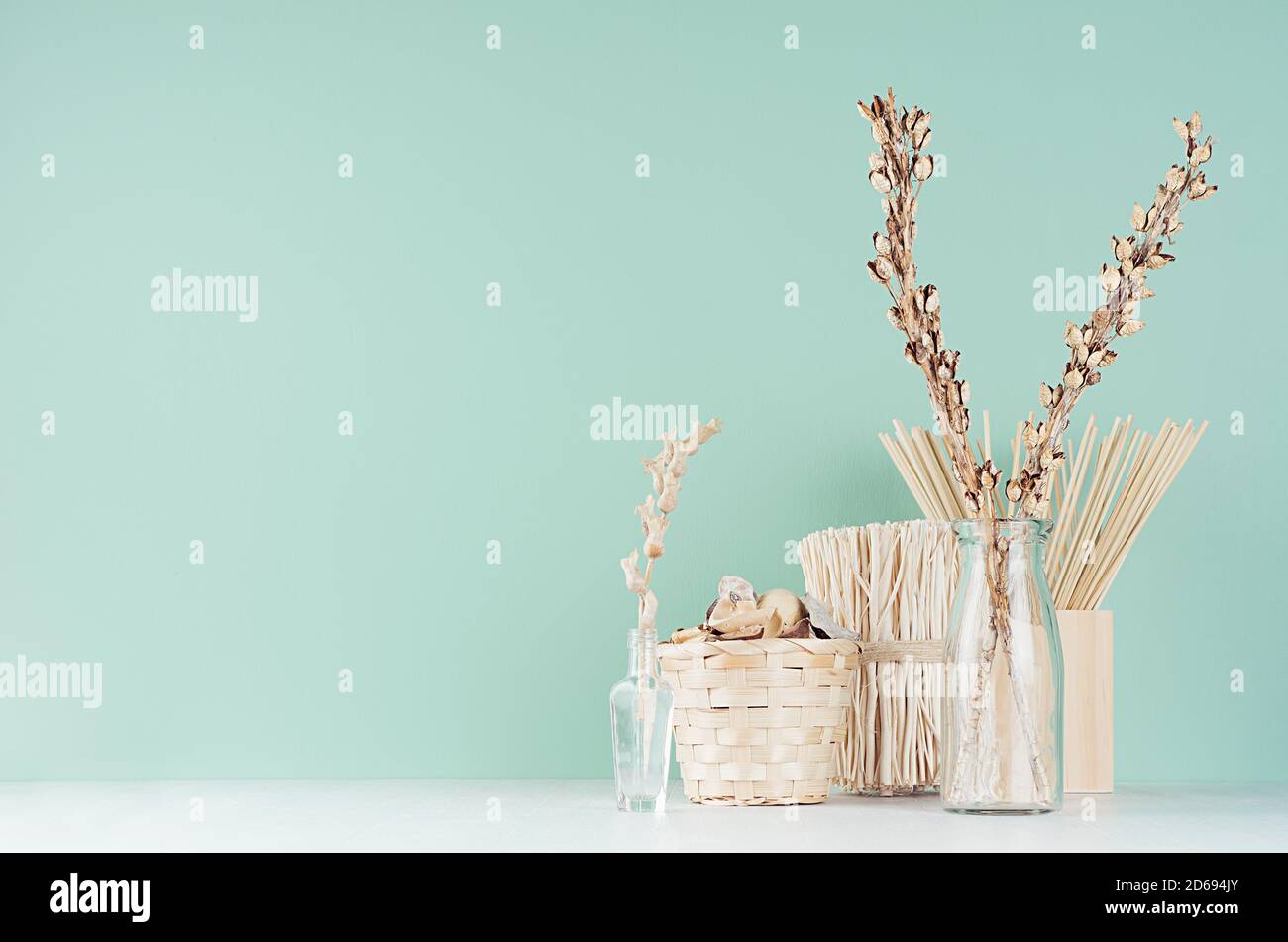 Interni contemporanei in trendy menthe color menta con piante secche beige, fiori, mazzo, cesto e vasi di vetro su un tavolo di legno bianco chiaro e morbido. Foto Stock