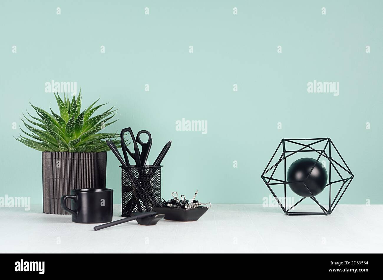 Luogo di lavoro primaverile con cancelleria nera, libri, caffè, modello astratto di atomo, pianta di aloe in elegante menthe verde su tavolo di legno bianco, Foto Stock