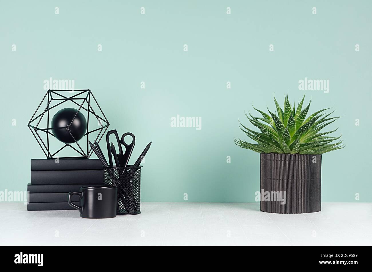 Interni semplici e minimalistici per ufficio con cancelleria nera, libri, caffè, aloe plant, scultura astratta in menthe verde all'interno su bianco WO Foto Stock