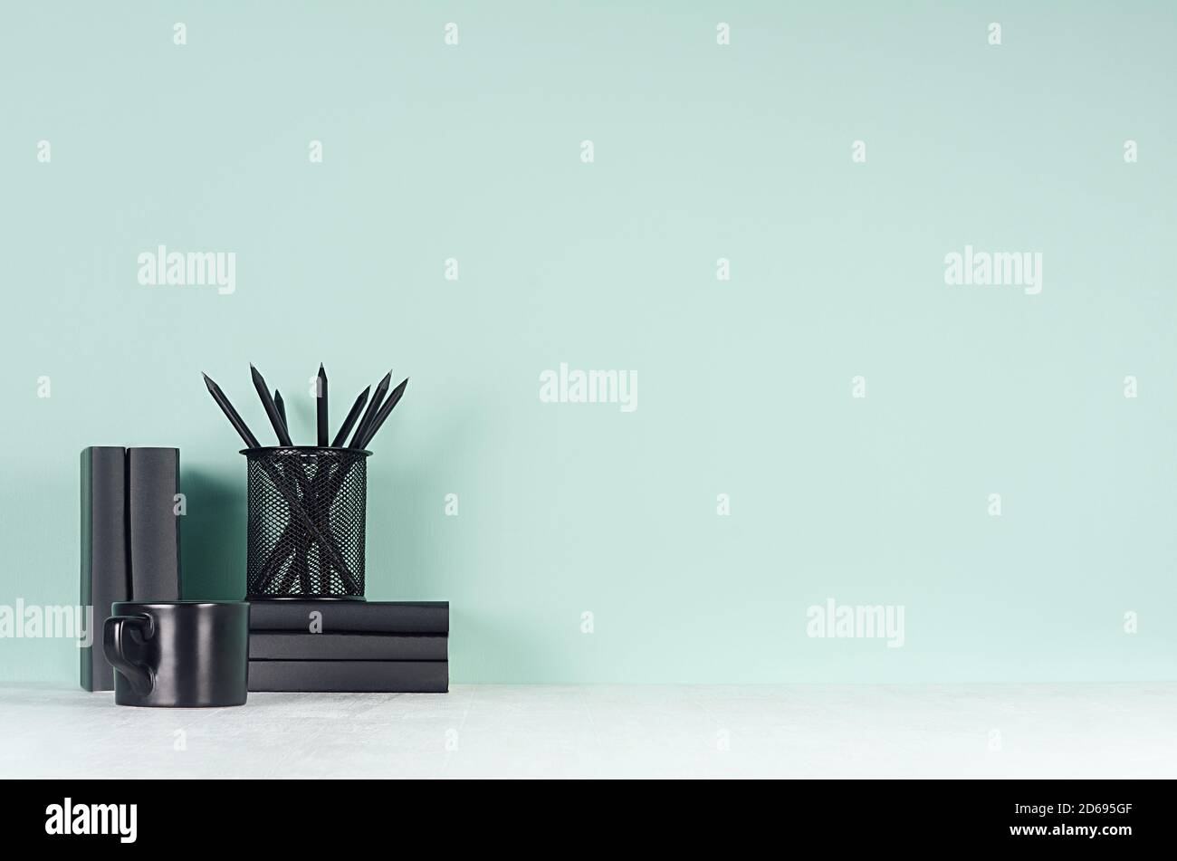 Elegante menta verde menthe interni dell'ufficio con cancelleria nera, libri, tazza di caffè su tavola di legno bianco chiaro morbido, spazio copia. Foto Stock