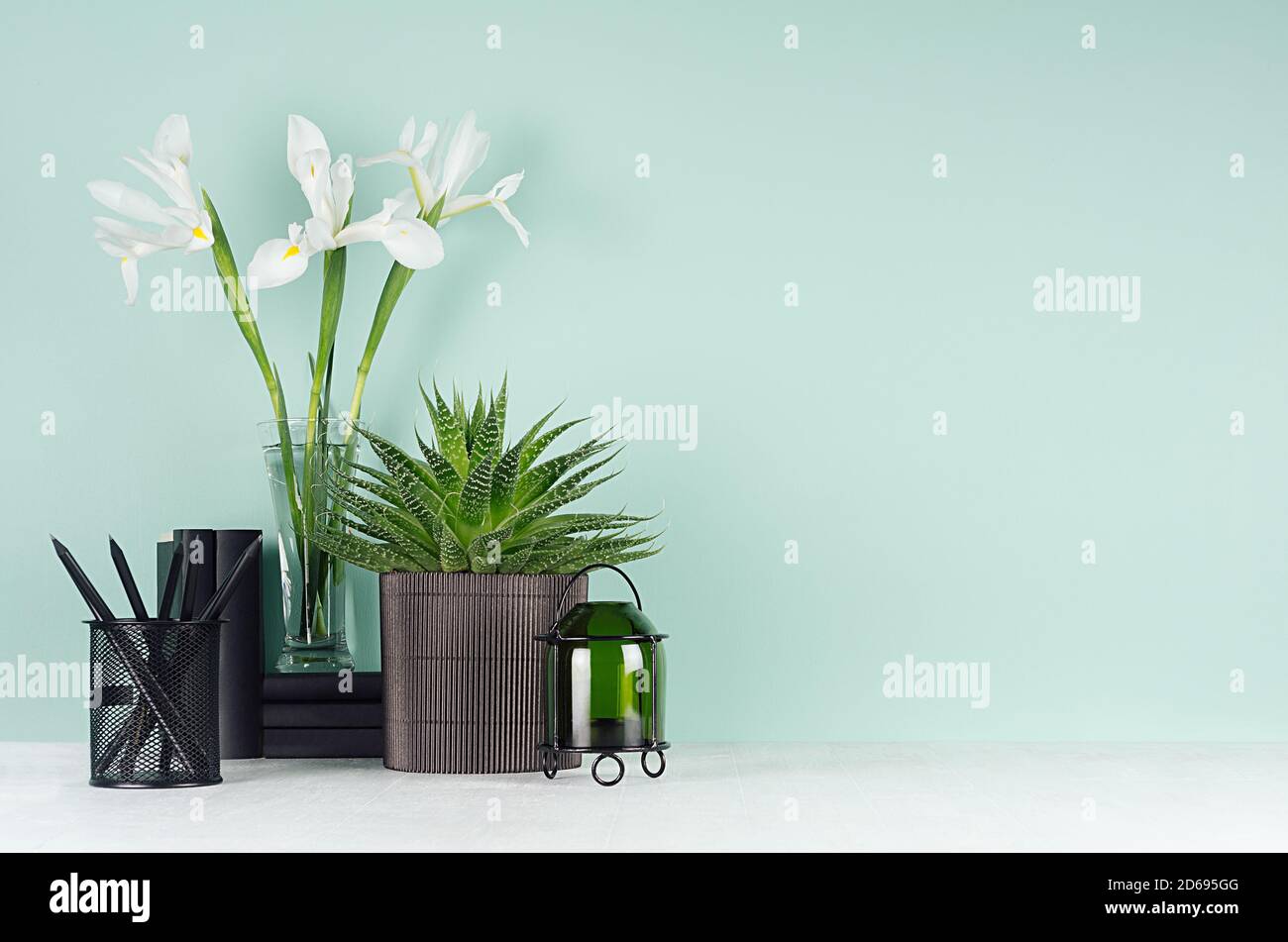 Primavera verde menta menthe interno d'ufficio con cancelleria nera, libri, verde vaso pianta di aloe, fresco bianco iride bouquet, candelabro su li soft Foto Stock