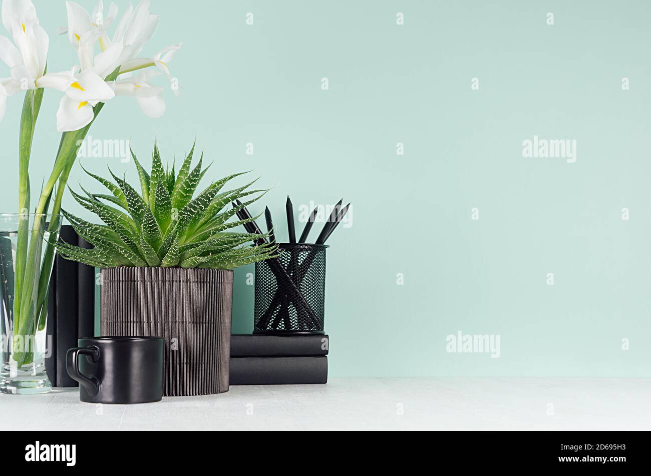 Menta verde primavera menthe interno dell'ufficio con cancelleria nera, libri, tazza di caffè, aloe verde, bouquet di iris bianco fresco su morbido legno bianco chiaro bo Foto Stock