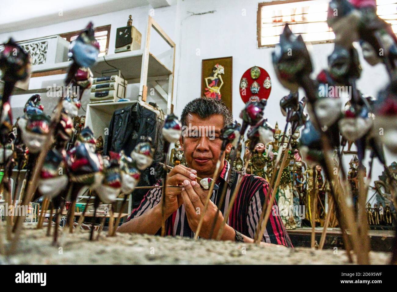 Un artigiano dipinge un burattino nella Galleria Cupuumanik. Cupupanik Puppets Gallery, fondata nel 1970, ha esportato burattini di varie dimensioni e forme per souvenir, collezioni, o spettacoli in vari paesi come il Belgio, l'America, l'Inghilterra, ecc. in mezzo alla pandemia di Covid-19, ora sopravvivono sulla vendita di mercato online. I prezzi medi dei burattini in questa galleria variano da 10,000 IDR a 1000,000 IDR secondo la taglia. Foto Stock