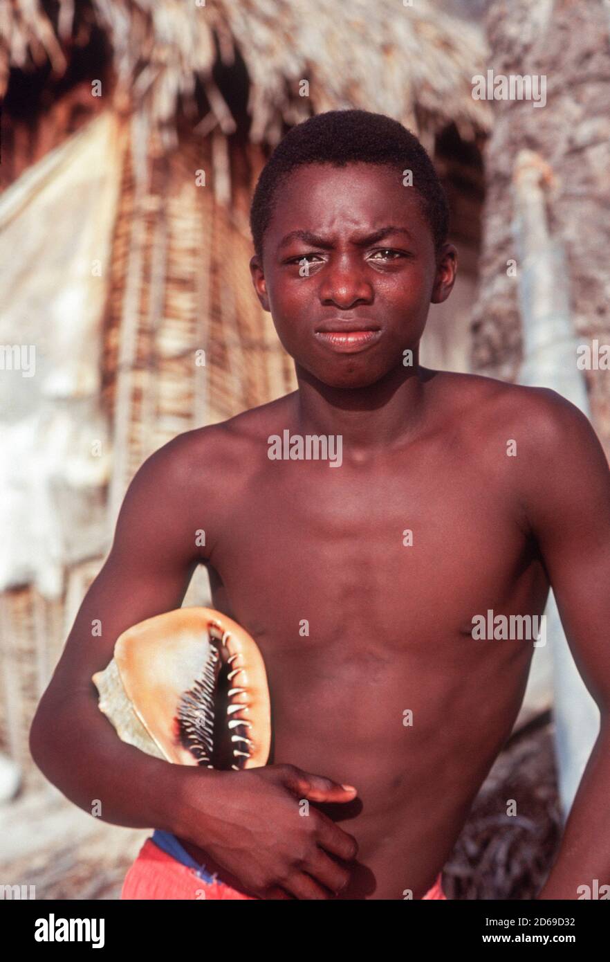 Ragazzo giovane con una conchiglia su una piccola isola al largo della costa dell'Honduras. Foto Stock