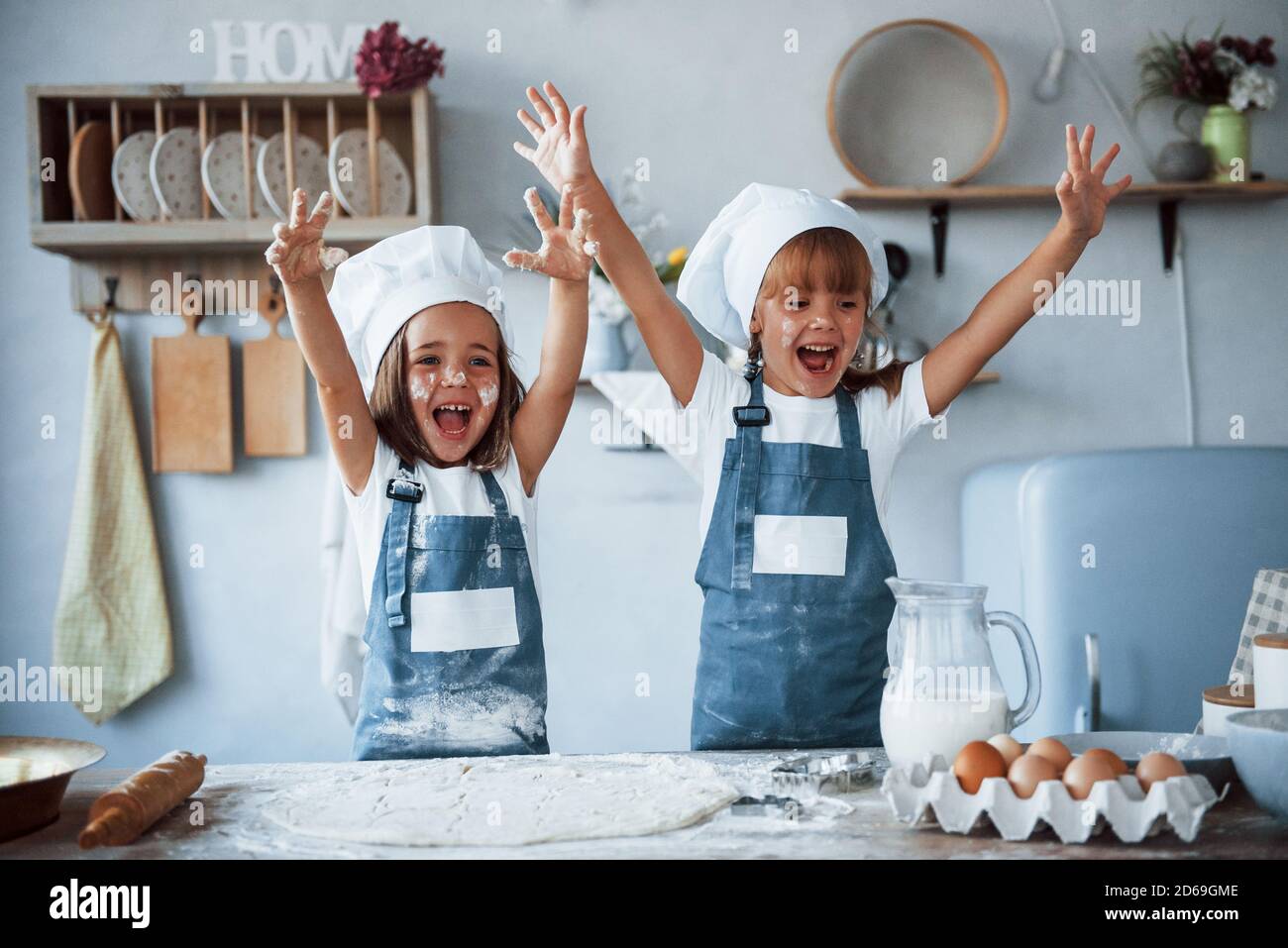 Divertirsi durante il processo. Bambini in famiglia in uniforme bianca dello chef che preparano il cibo in cucina Foto Stock
