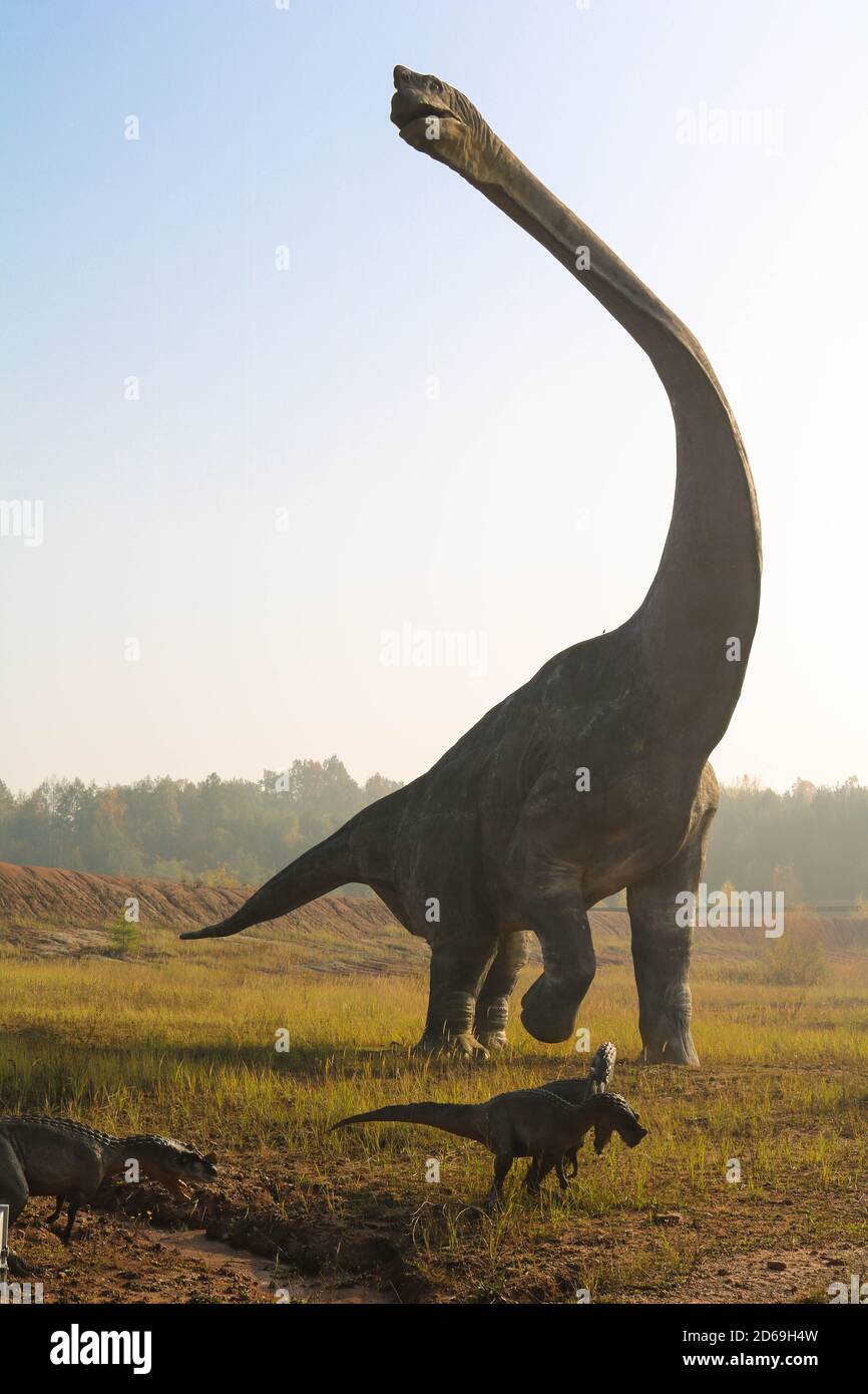 Un enorme dinosauro Sauropodomorph con un collo molto lungo la compagnia di  dinosauri più piccoli attraversa i campi Foto stock - Alamy
