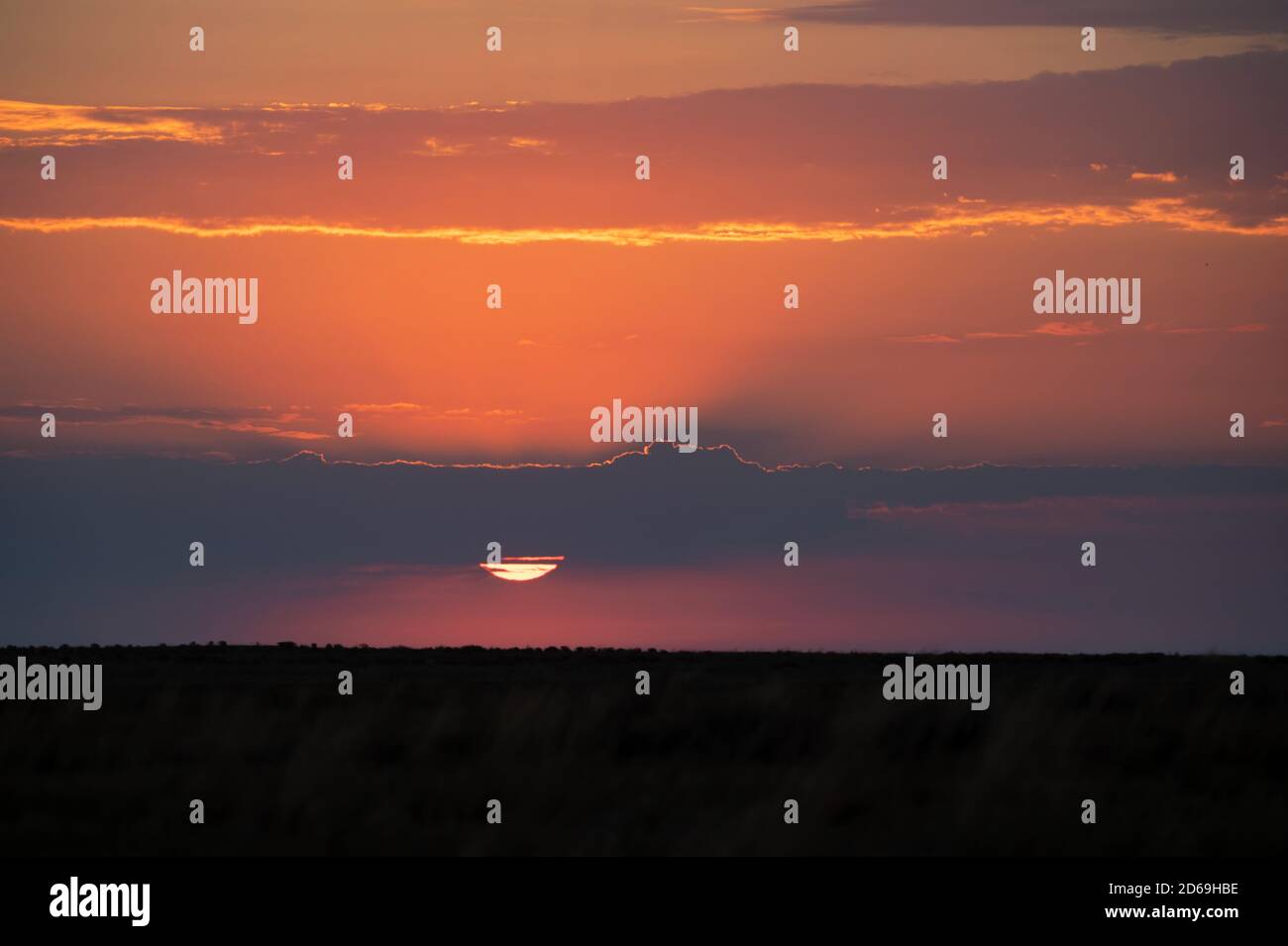 Cielo scenografico al tramonto con nuvole scure e sole rosso Foto Stock