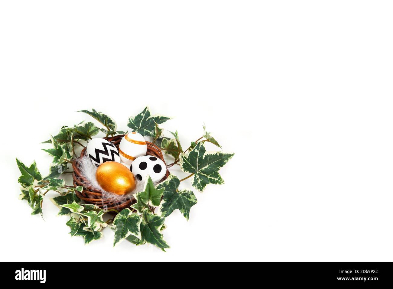Buona Pasqua. Uova dipinte in oro e nero in nido d'edera. Congratulazioni pasqua sfondo con copia spazio. Isolato su sfondo bianco. Foto Stock