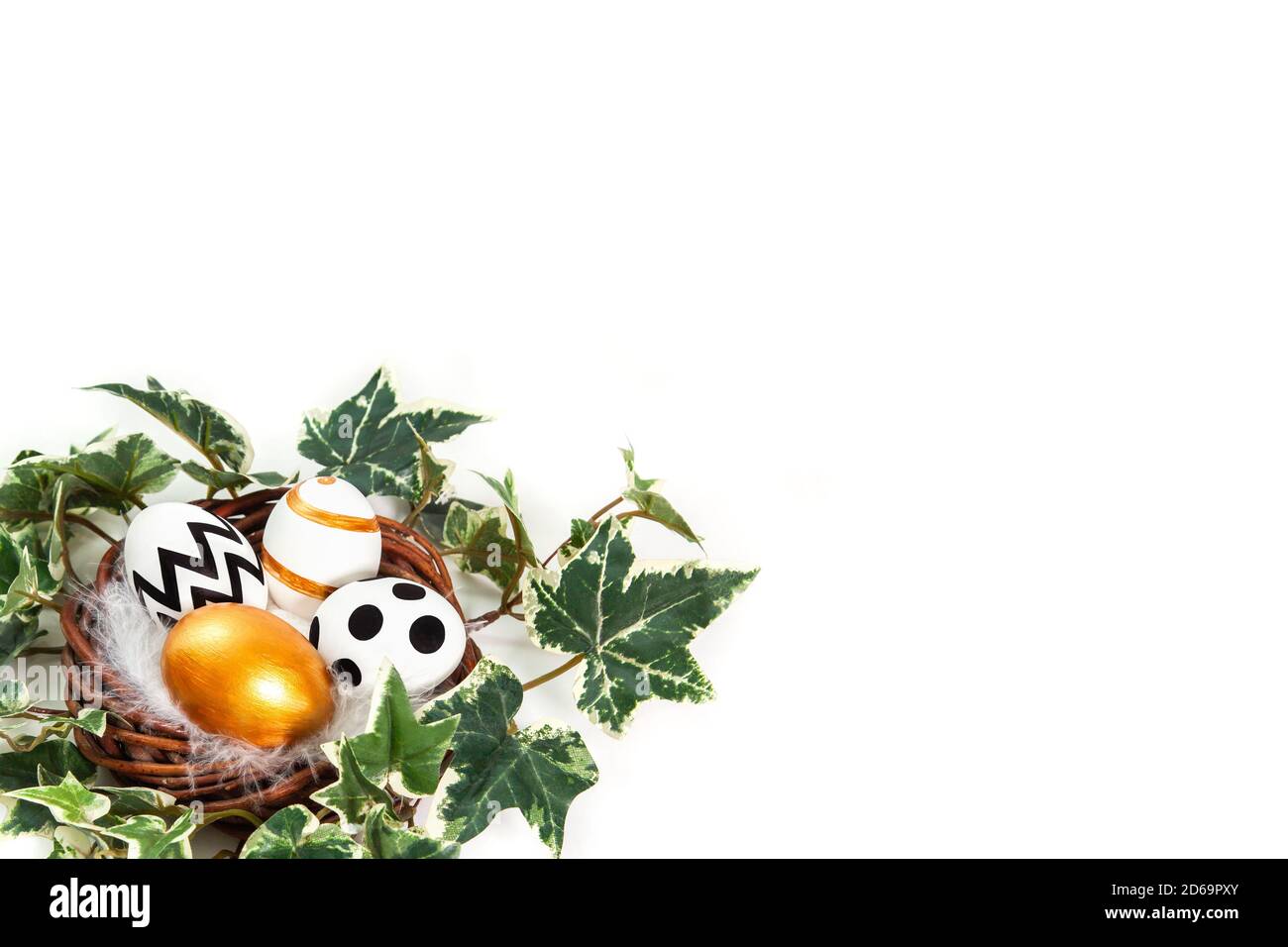 Buona Pasqua. Uova dipinte in oro e nero in nido d'edera. Congratulazioni pasqua background. Isolato su sfondo bianco con spazio per la copia. Foto Stock