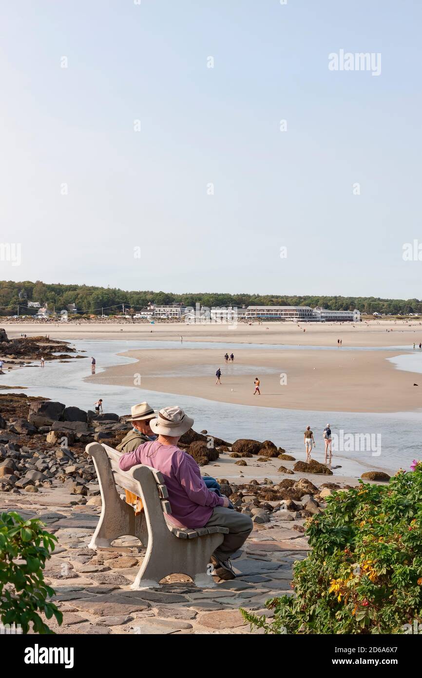 Uomini seduti e parlando su una panchina che si affaccia sulla spiaggia lungo la via marginale a Ogunquit, Maine, Stati Uniti. Foto Stock