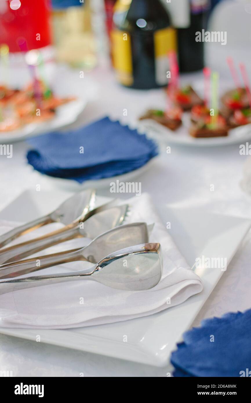 attrezzature per il servizio catering - pinze metalliche su piastra bianca. Foto Stock