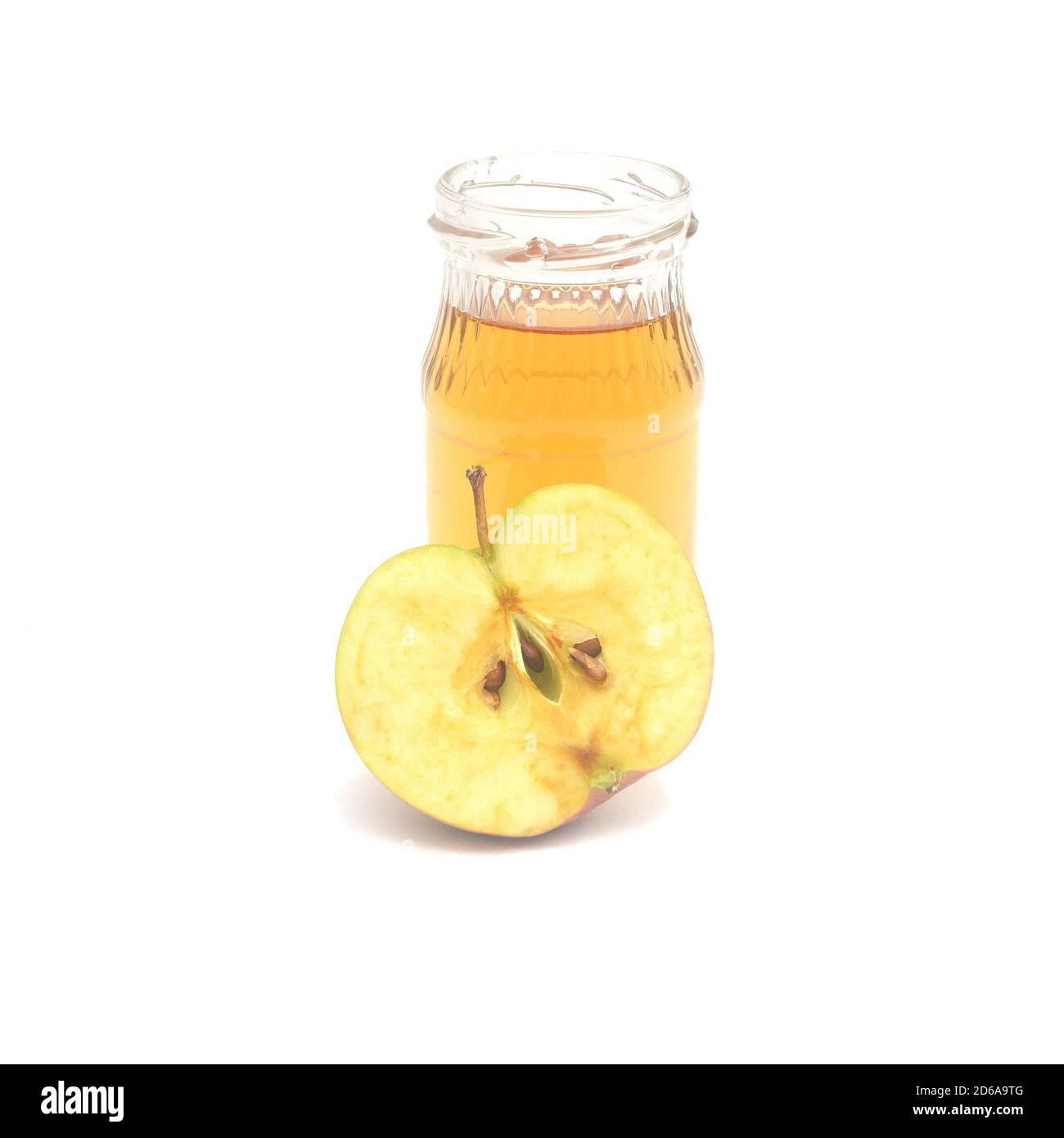 Una mezza mela e una piccola bottiglia di aceto di sidro di mele isolate su sfondo bianco. Foto Stock