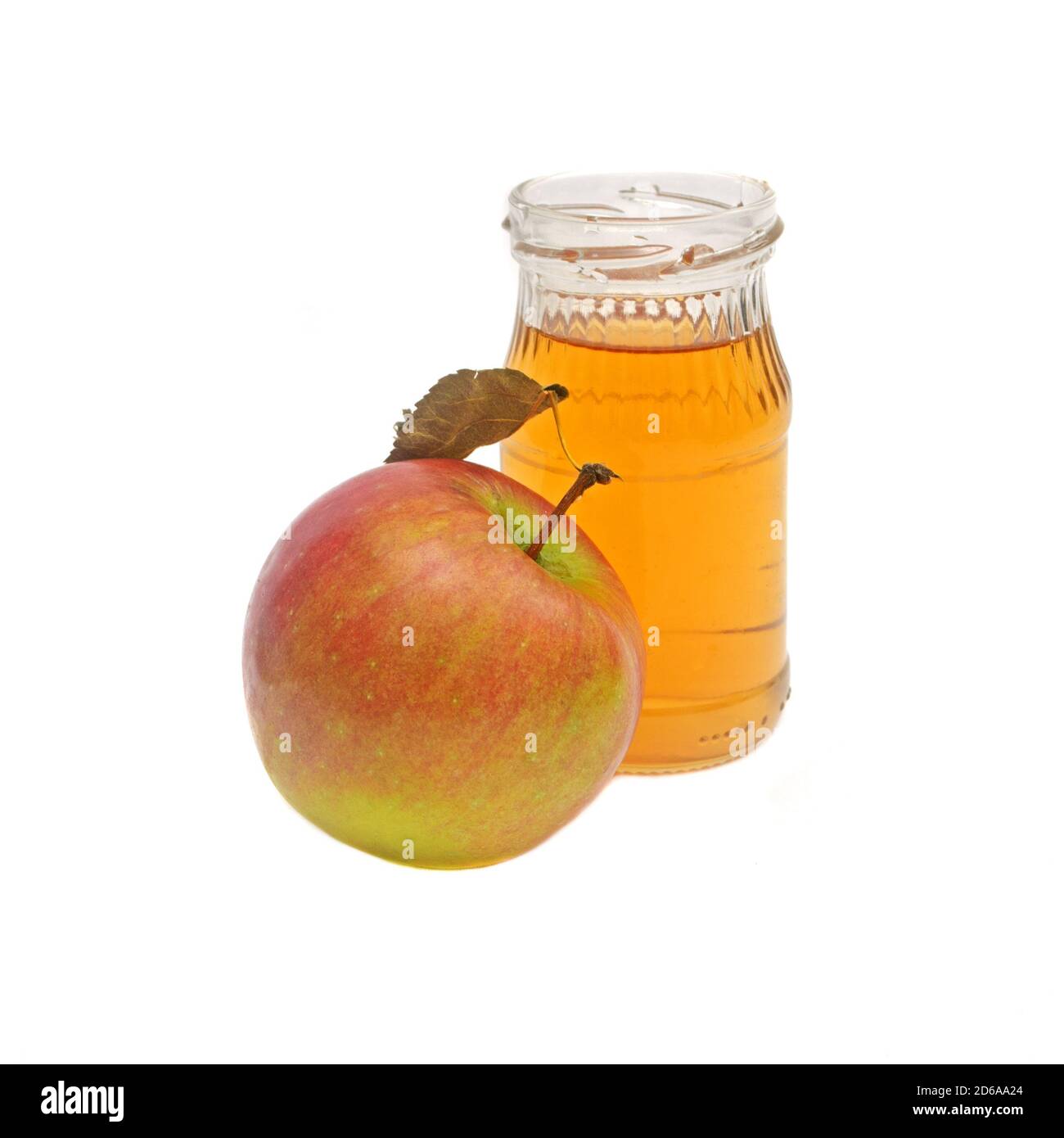 Una mela intera con foglia e una piccola bottiglia di aceto di sidro di mele isolato su fondo bianco. Foto Stock
