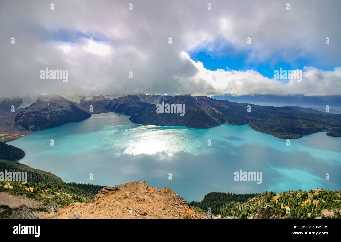 Panorama Ridge Trail nel Parco Provinciale Garibaldi, BC. La vista aerea sul lago turchese circondato da montagne innevate. Cielo nuvoloso. Foto Stock