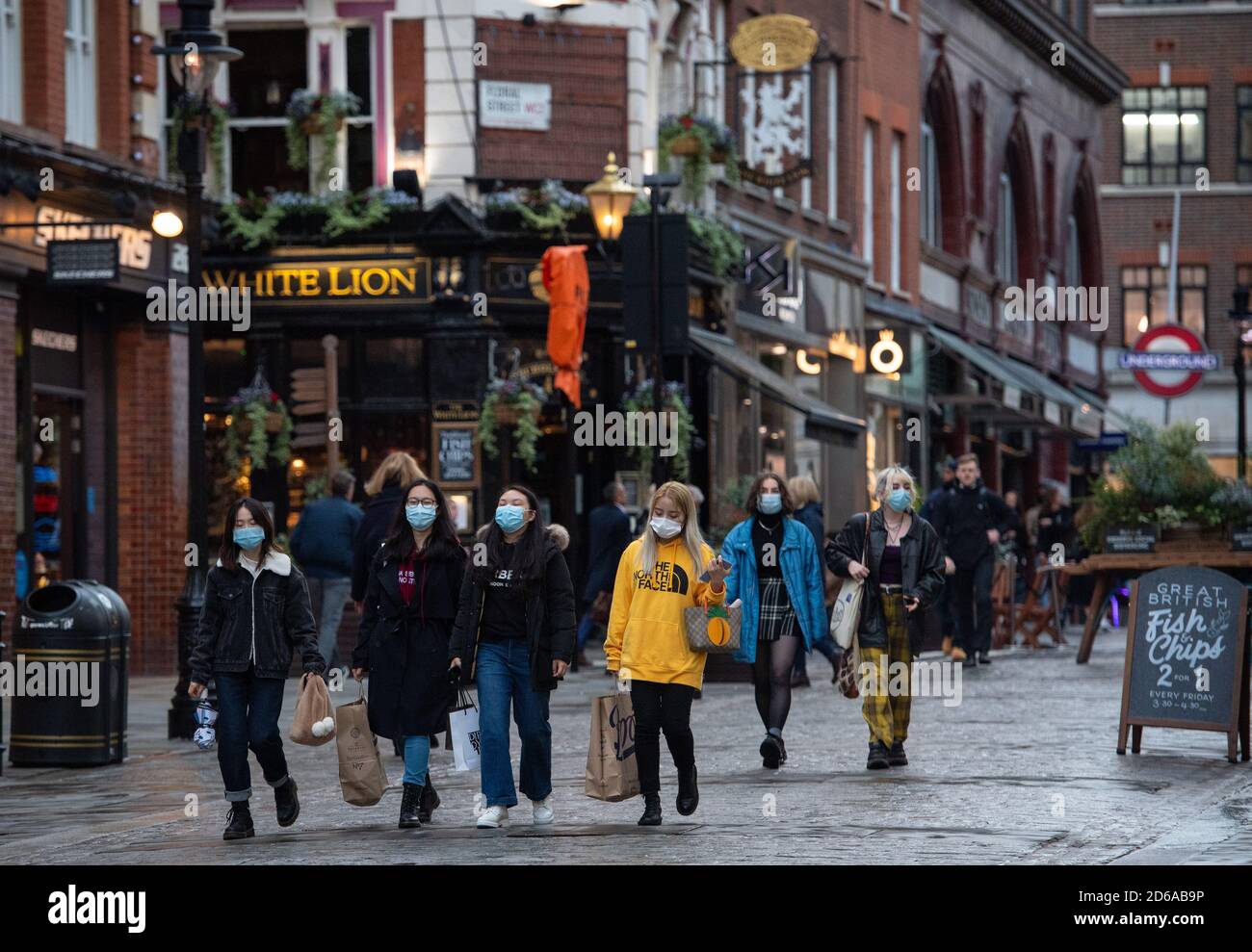 Persone che indossano maschere a Covent Garden, nel centro di Londra, dopo che il sindaco di Londra Sadiq Khan ha annunciato che Londra sarà trasferito alle restrizioni Tier 2 del coronavirus a partire dalla mezzanotte del venerdì. Foto Stock