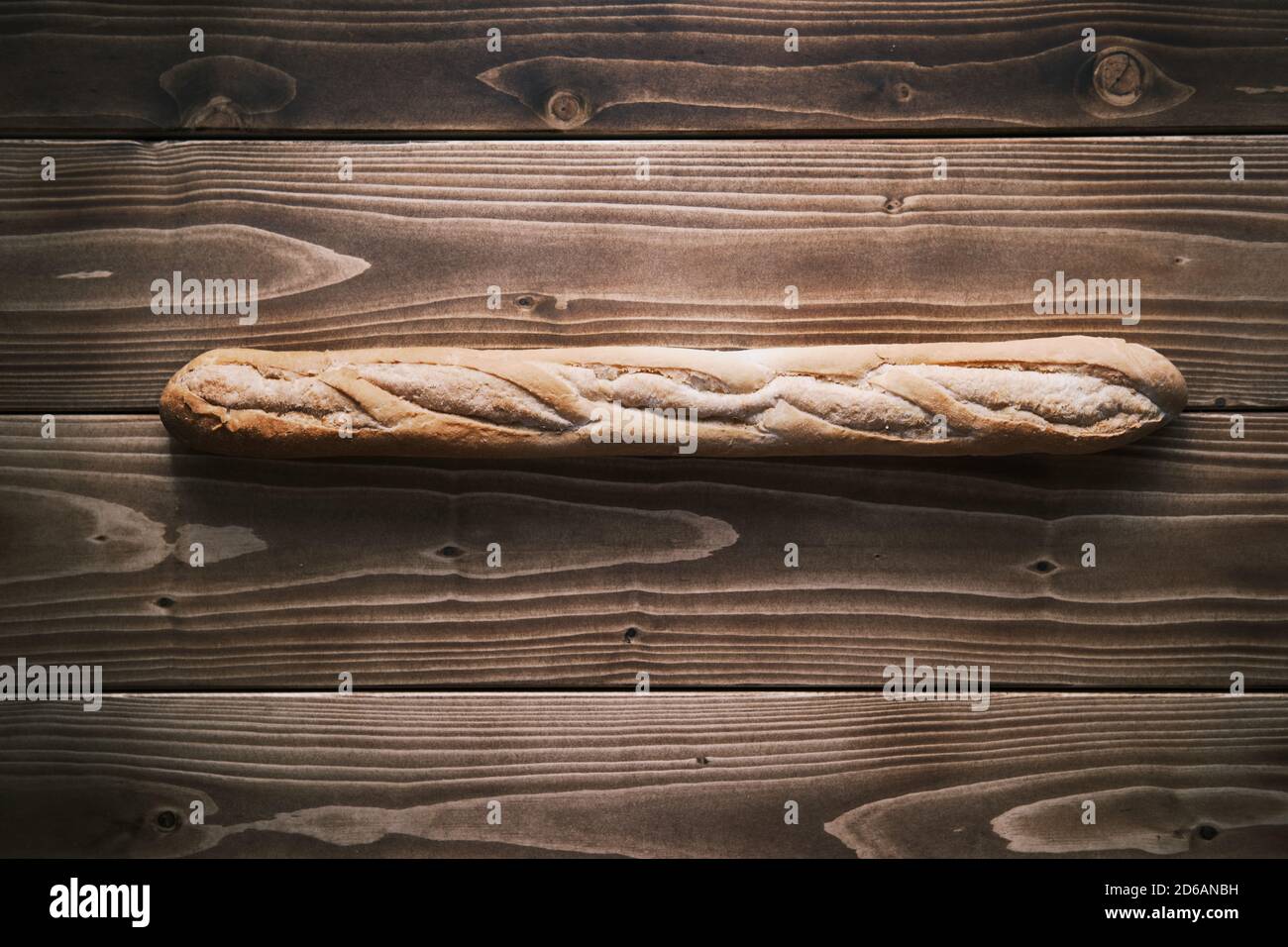 Colpo verticale di una baguette francese fresca su un tavolo di legno. Pronto a mangiare Foto Stock