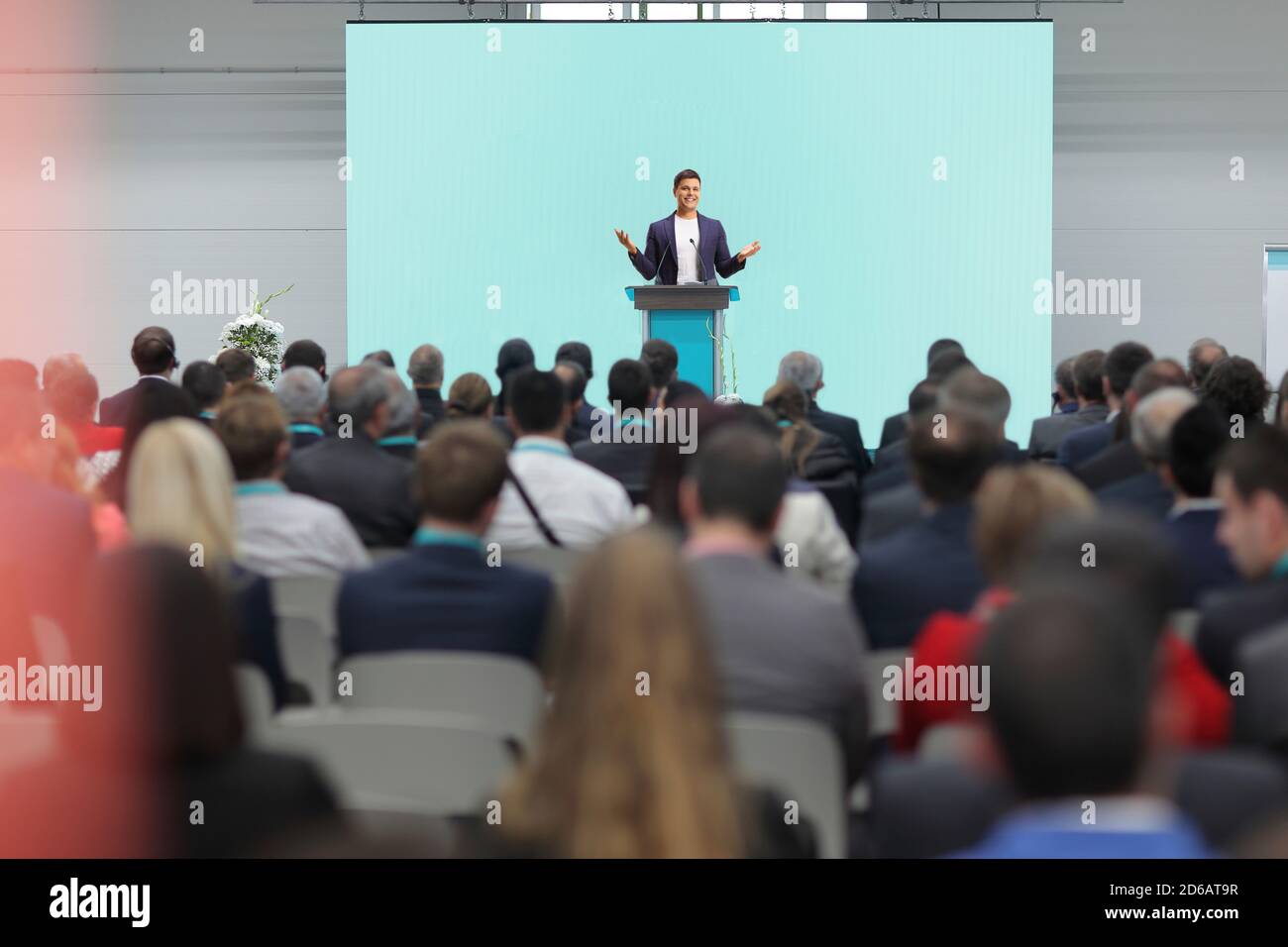 Uomo che parla su un piedistallo di fronte a una conferenza di un pubblico isolato su sfondo bianco Foto Stock