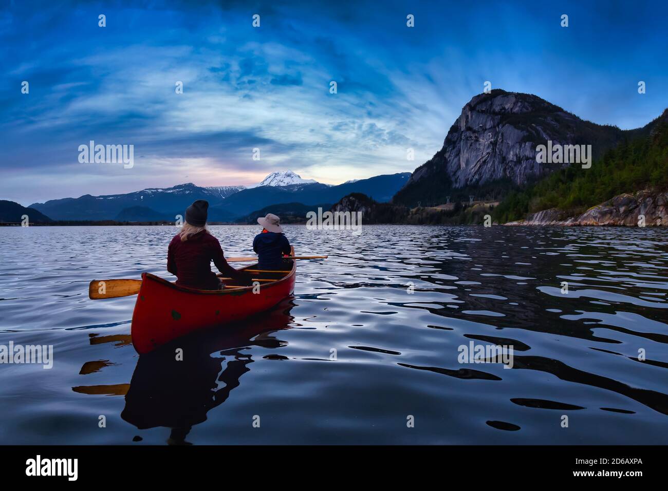 Persone avventurose su una canoa con le montagne dietro Foto Stock