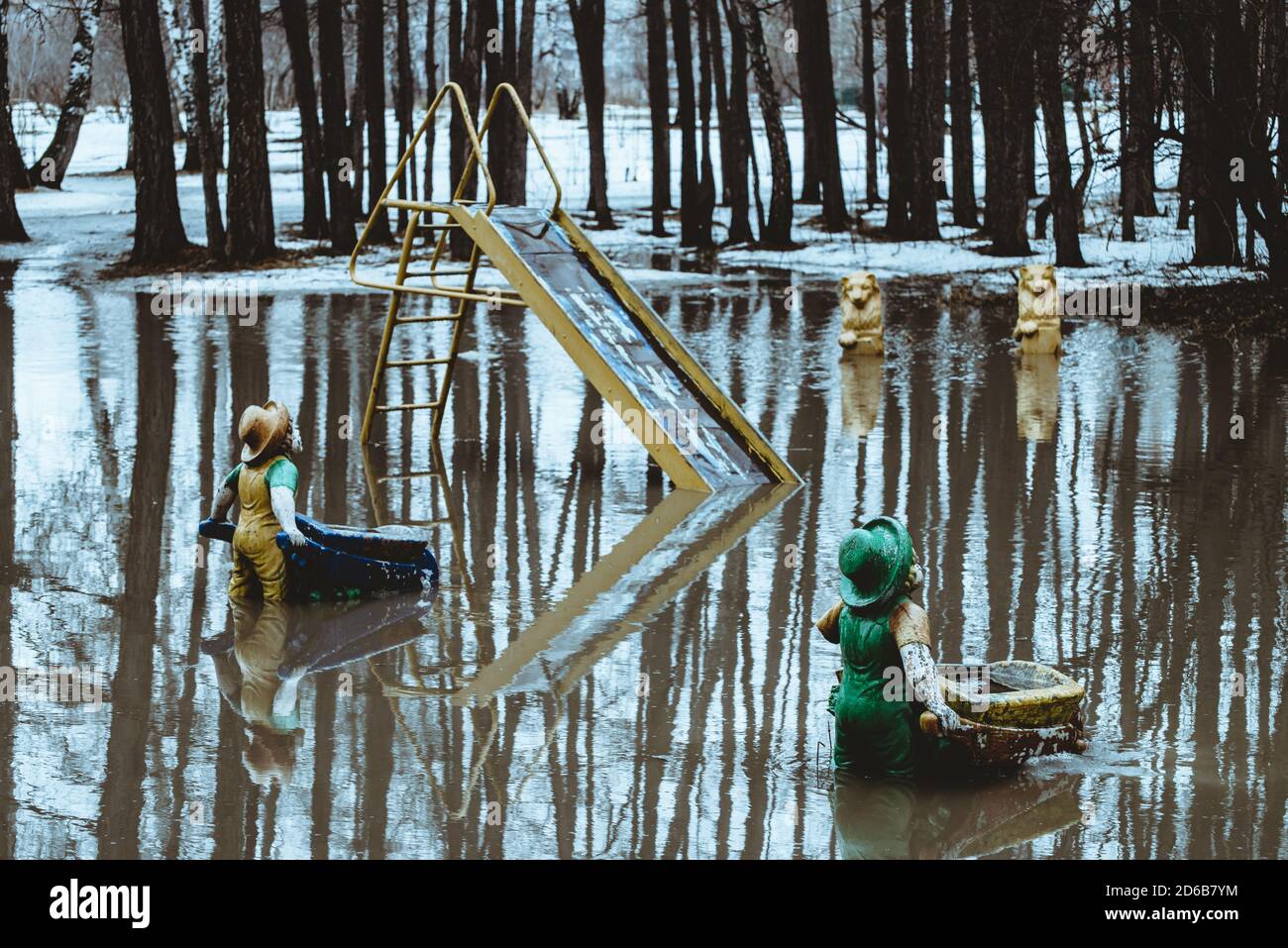 Figurine in forma di gnomi si trova con la schiena con i barili in acqua in primavera nella realtà russa. La neve si sta sciogliendo, creando un enorme puddle. Atmosfera Foto Stock