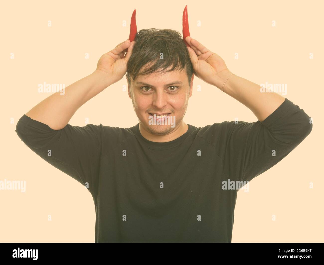 Studio di pazzo uomo caucasico con peperoni rossi come corna sorridenti Foto Stock