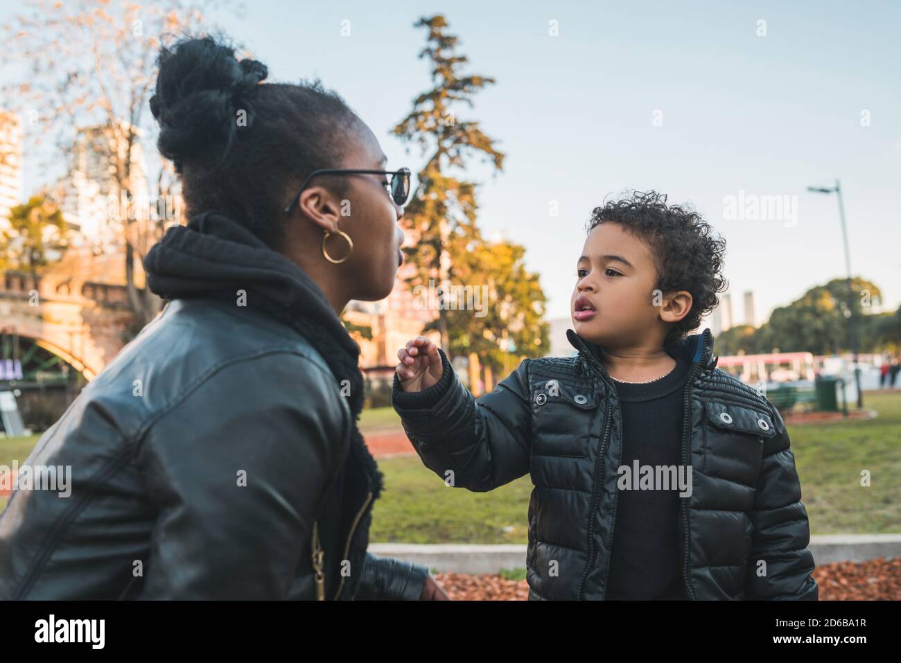 Ritratto di una madre afroamericana con suo figlio in piedi all'aperto nel parco, divertendosi. Famiglia monoparentale. Foto Stock