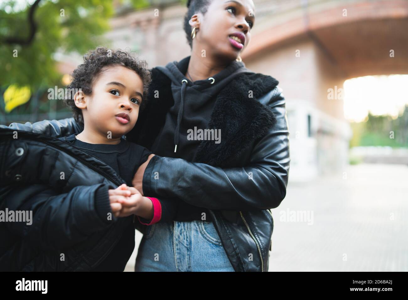 Ritratto di una madre afroamericana con suo figlio in piedi all'aperto nel parco, divertendosi. Famiglia monoparentale. Foto Stock