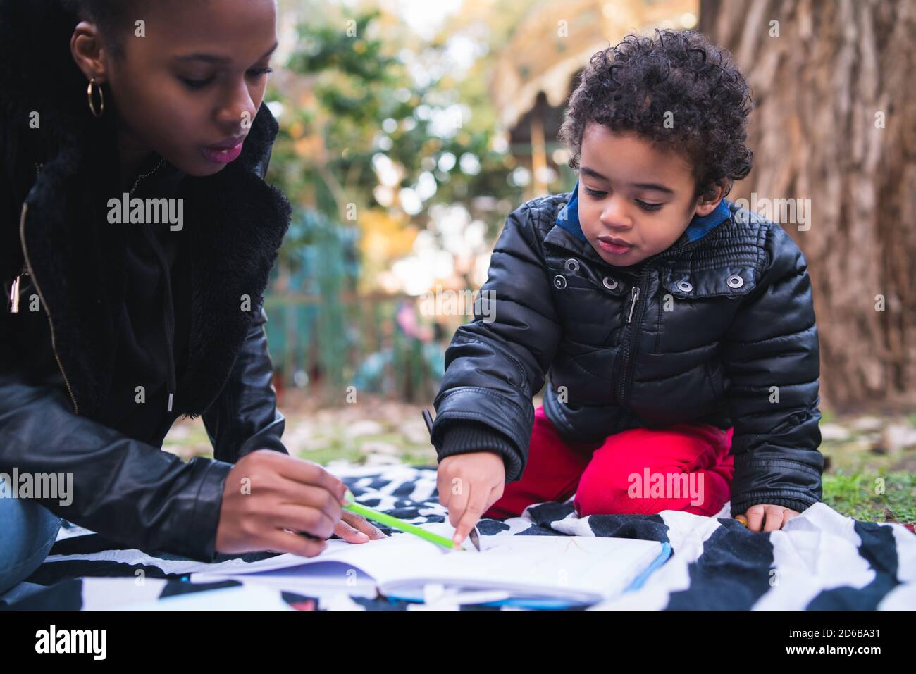 Ritratto di una madre afroamericana con suo figlio che gioca e si diverte insieme all'aperto nel parco. Famiglia monoparentale. Foto Stock