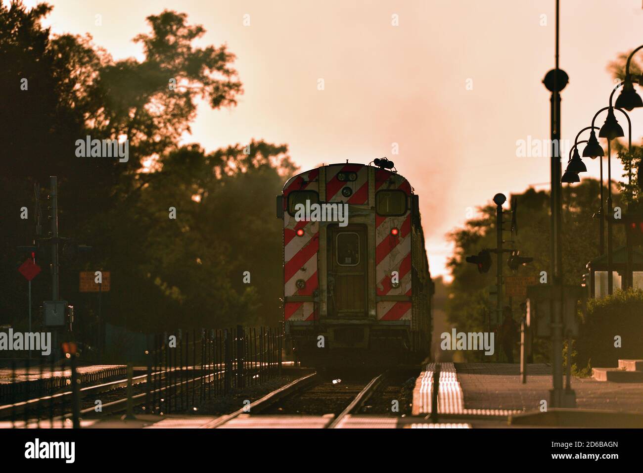 Bensenville, Illinois, Stati Uniti. Un treno per pendolari Metra da Chicago dopo aver lasciato la stazione di Bensenville, Illinois, al tramonto veloce. Foto Stock