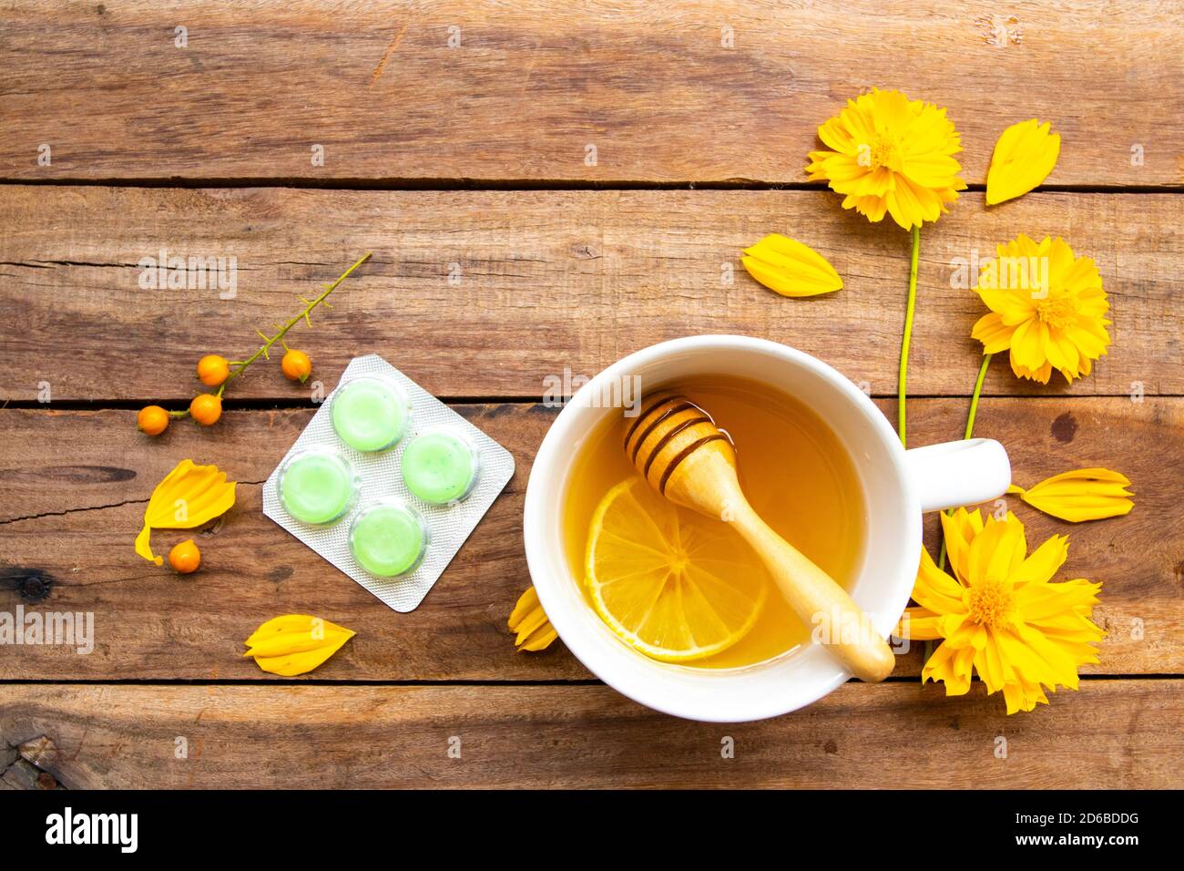 erbe bevande salutari miele caldo limone e losanga per la salute cura mal di gola con fetta di limone, fiori cosmo disposizione piatto stile di posa su legno Foto Stock