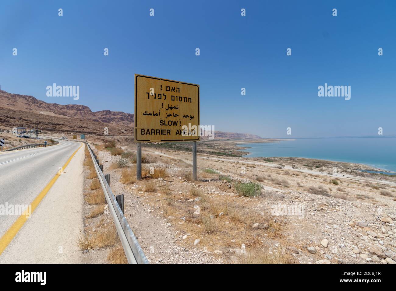 Strada n° 90 nei pressi del Mar Morto, Israele. Una vista del Mar Morto, e un segno giallo che dice in ebraico, arabo e inglese, 'hanno un checkpoint di fronte Foto Stock