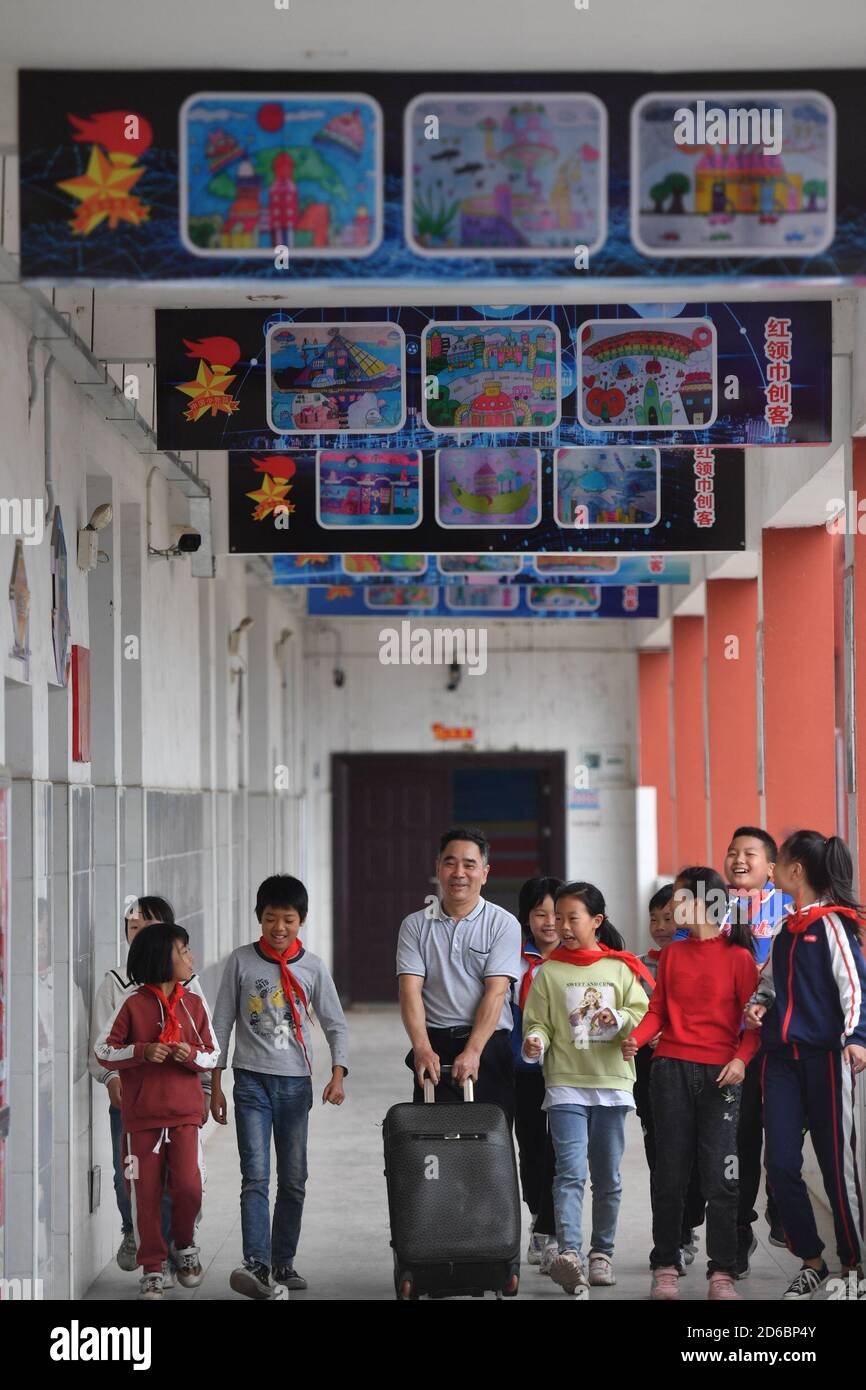 (201016) -- LUXI, 16 ottobre 2020 (Xinhua) -- li Xuezhan (C) cammina con la sua valigia contenente sussidi didattici fatti a mano a scuola nella contea di Luxi, nella provincia di Jiangxi della Cina orientale, 14 ottobre 2020. Ogni volta che li Xuezhan entra nella scuola centrale nella città di Xuanfeng della contea di Luxi con la sua valigia piena di sussidi didattici fatti a mano, sarà seguito e circondato da studenti. Li, 58 anni, divenne insegnante di scienze nel 1996. A causa della mancanza di ausili didattici, ha dovuto raccogliere bottiglie vuote, legno, pneumatici rotti e trasformarli in ausili didattici per la classe scientifica. Ora come condizionati di insegnamento della scuola Foto Stock