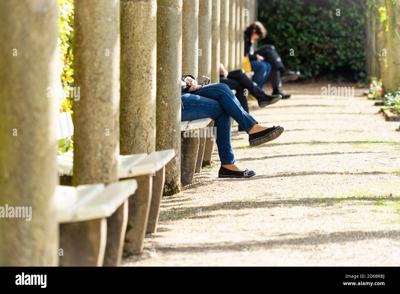 Persone sedute a distanza sociale in una galleria con solo le gambe visibili Foto Stock