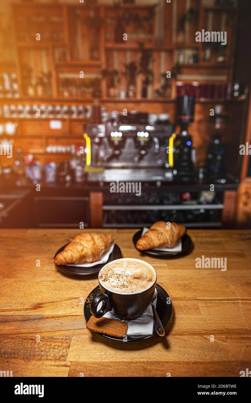 Bevanda di caffè servito con croissant sul tavolo di legno con blur caff come sfondo Foto Stock